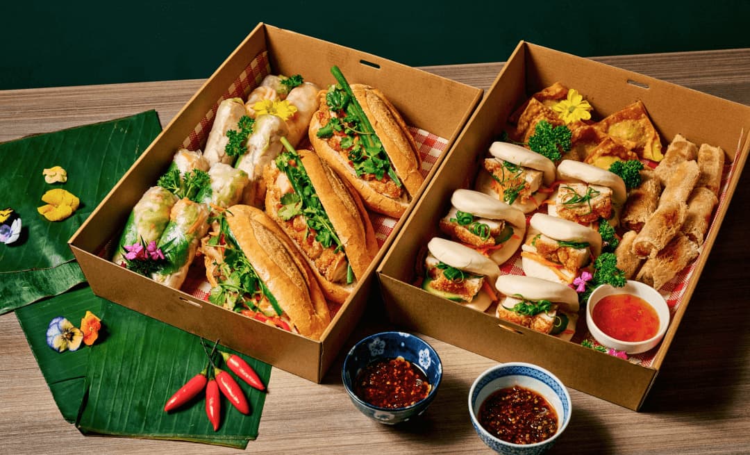 Two catering boxes of Vietnamese bánh mì and share plates from ĂN ĐI